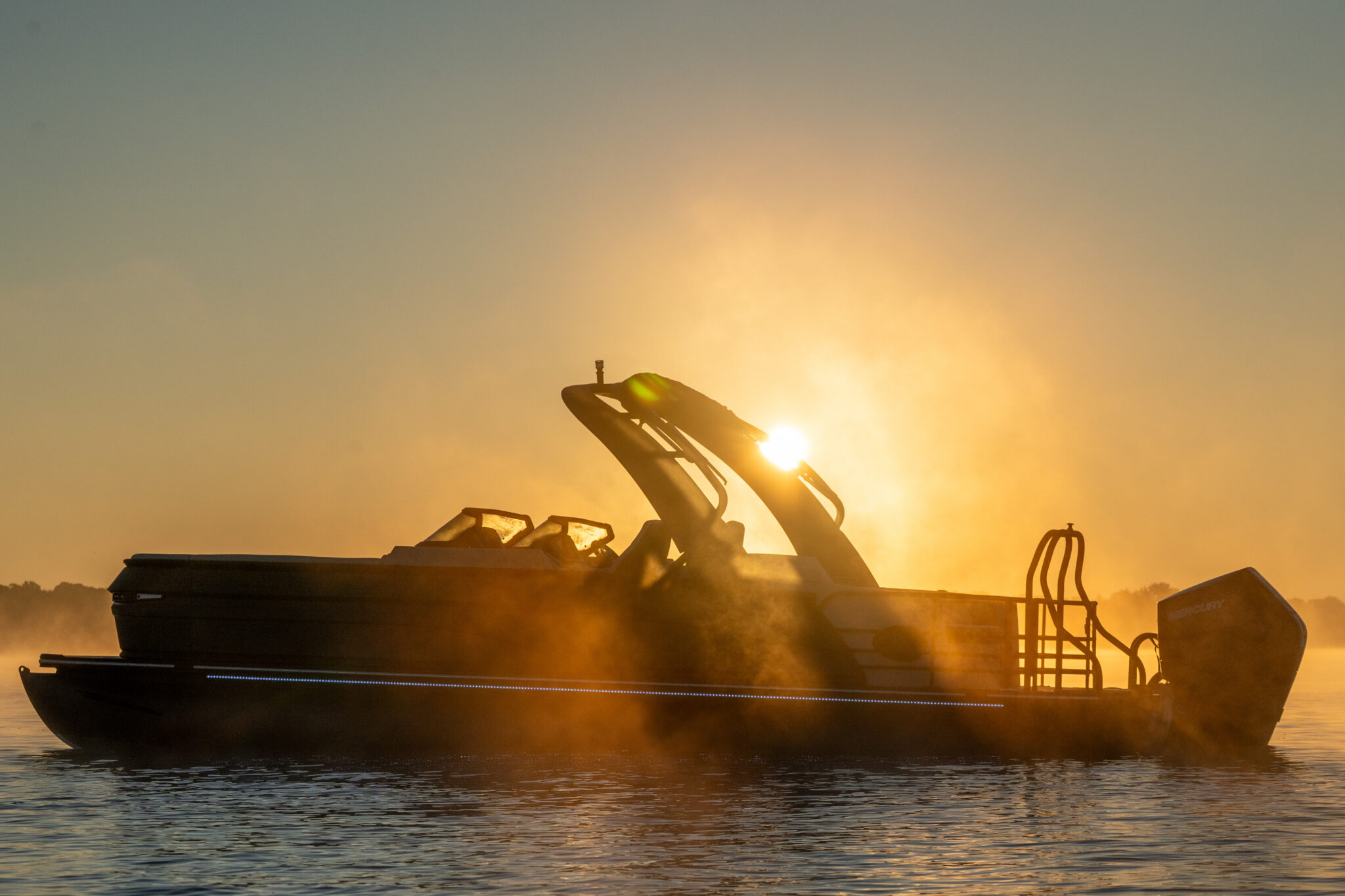 Boat silhouetted against a golden sunrise or sunset over water.